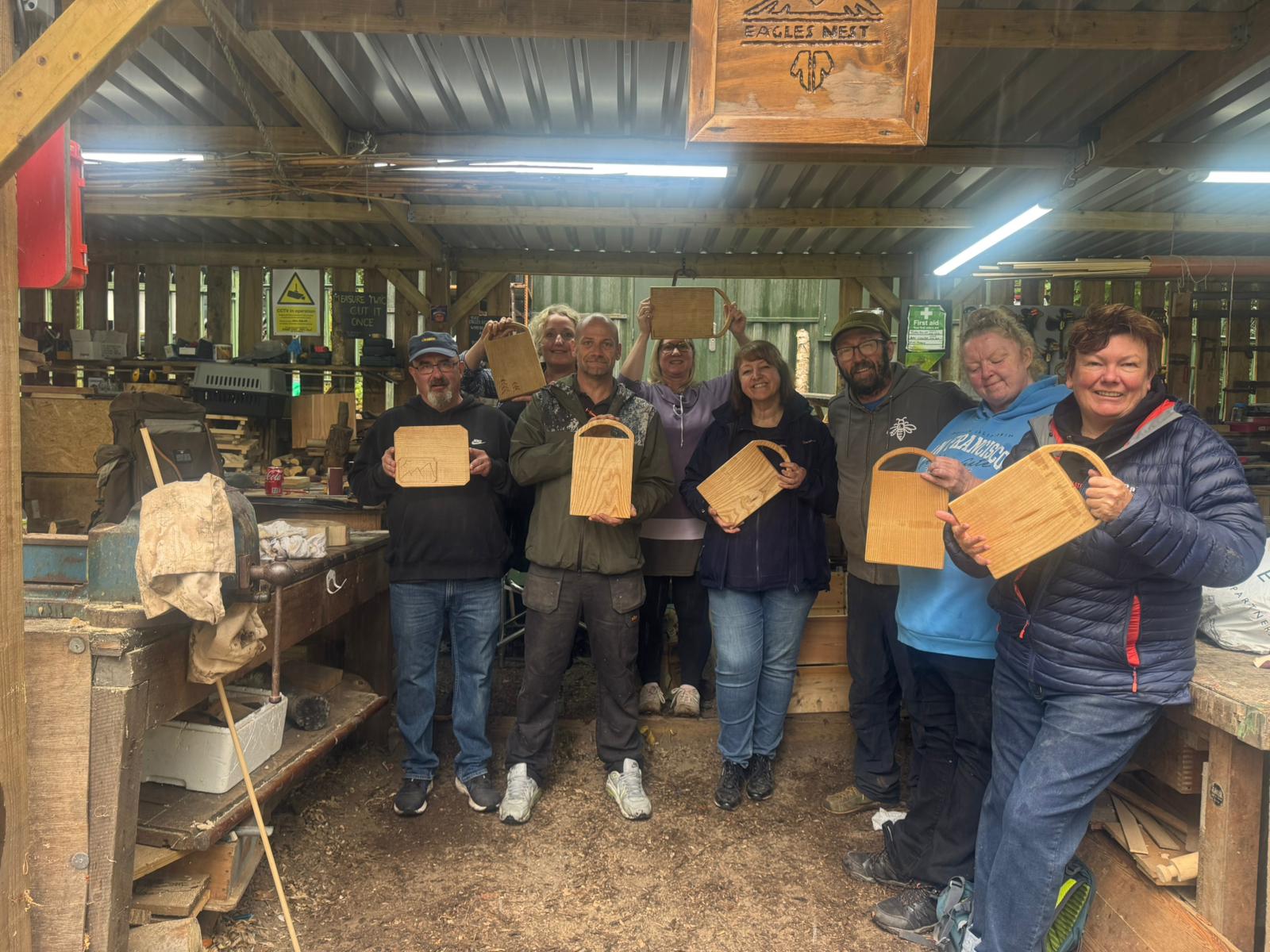 Woodcraft participants holding their handmade wooden pieces