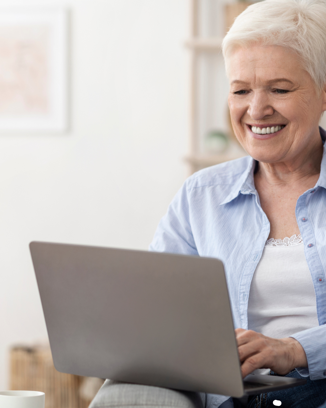 Older woman smiling while using a laptop at home