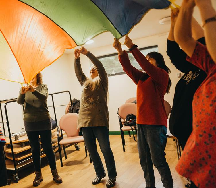 Women taking part in a colourful parachute activity during The Change programme